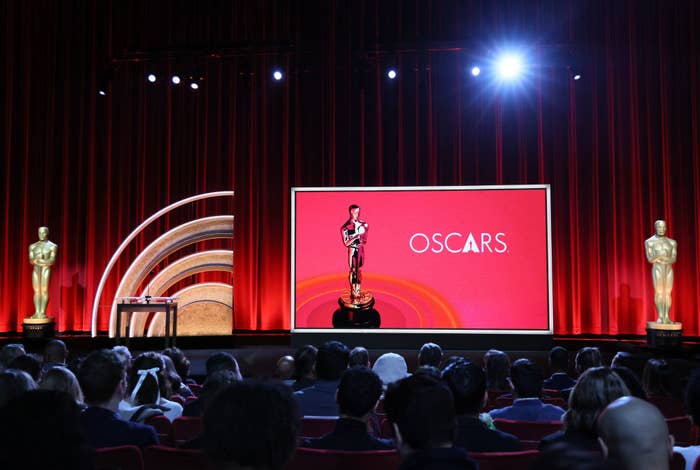 Stage with Oscar statue and "OSCARS" on screen, audience in foreground, event setting