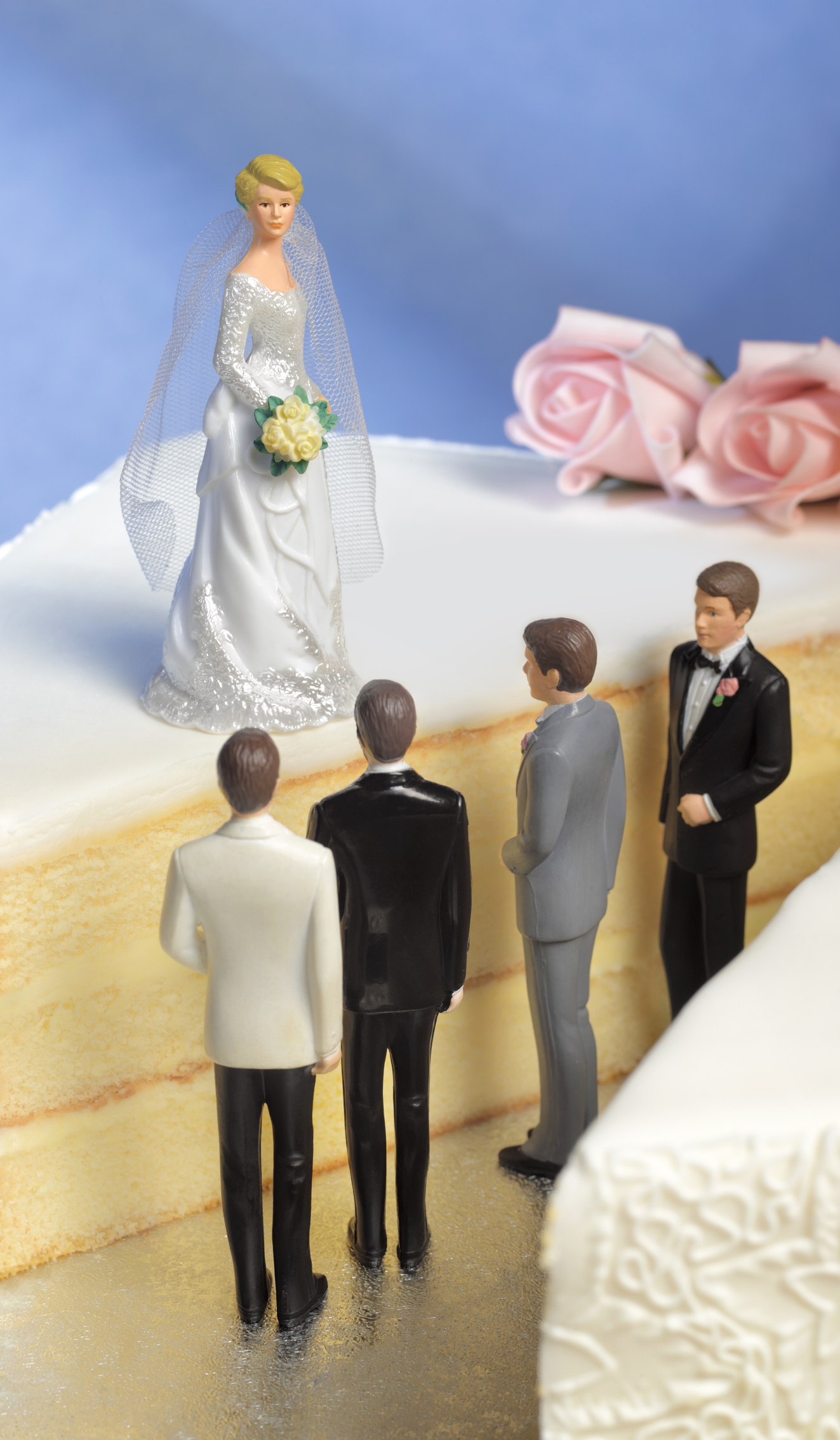 Bride figurine at the top of a cake with three groom figurines below, implying a choice