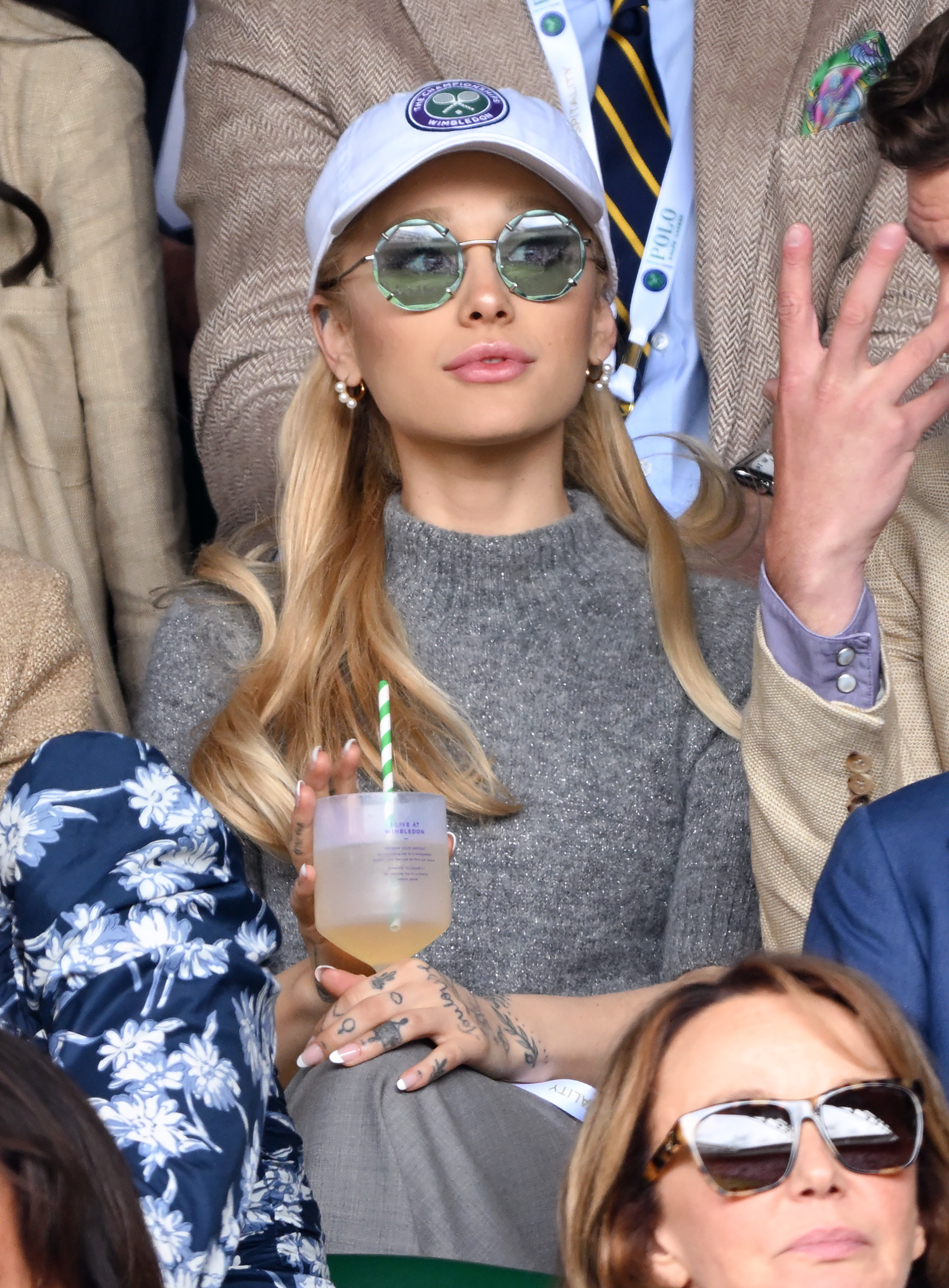 A closeup of ari in shades and a cap at a sporting event