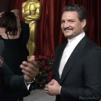 Antonio Banderas aplaudiendo con una estatuilla de los Oscar y un ramo de rosas en segundo plano