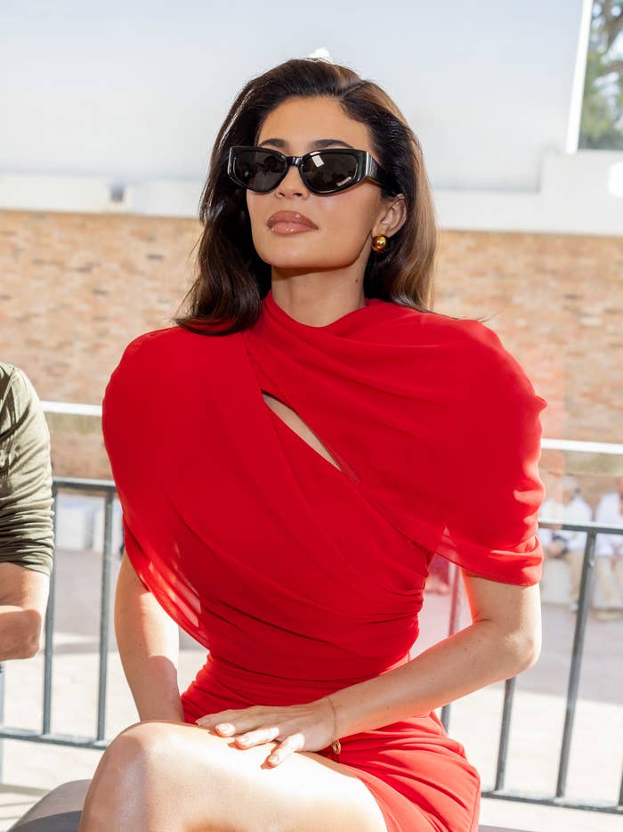 Kylie in a dress with full glam sitting and wearing sunglasses