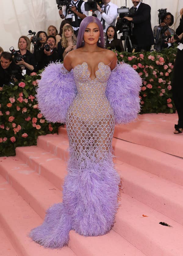 Kylie in a sheer, beaded gown with voluminous sleeves at a gala event, heavily tanned with long straight hair