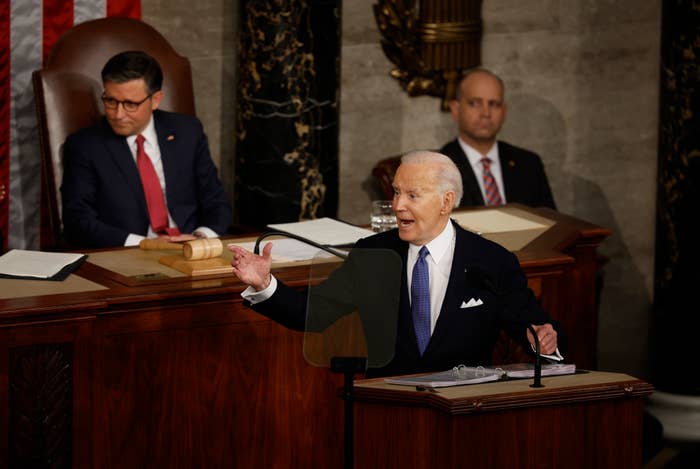 President Biden speaking at a podium in front of Speaker of the House Mike Johnson