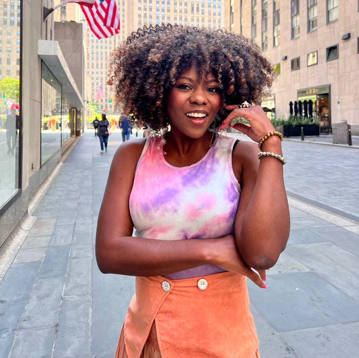 Patrice J. Williams wearing a tie-dye top and orange skirt smiling on a city street