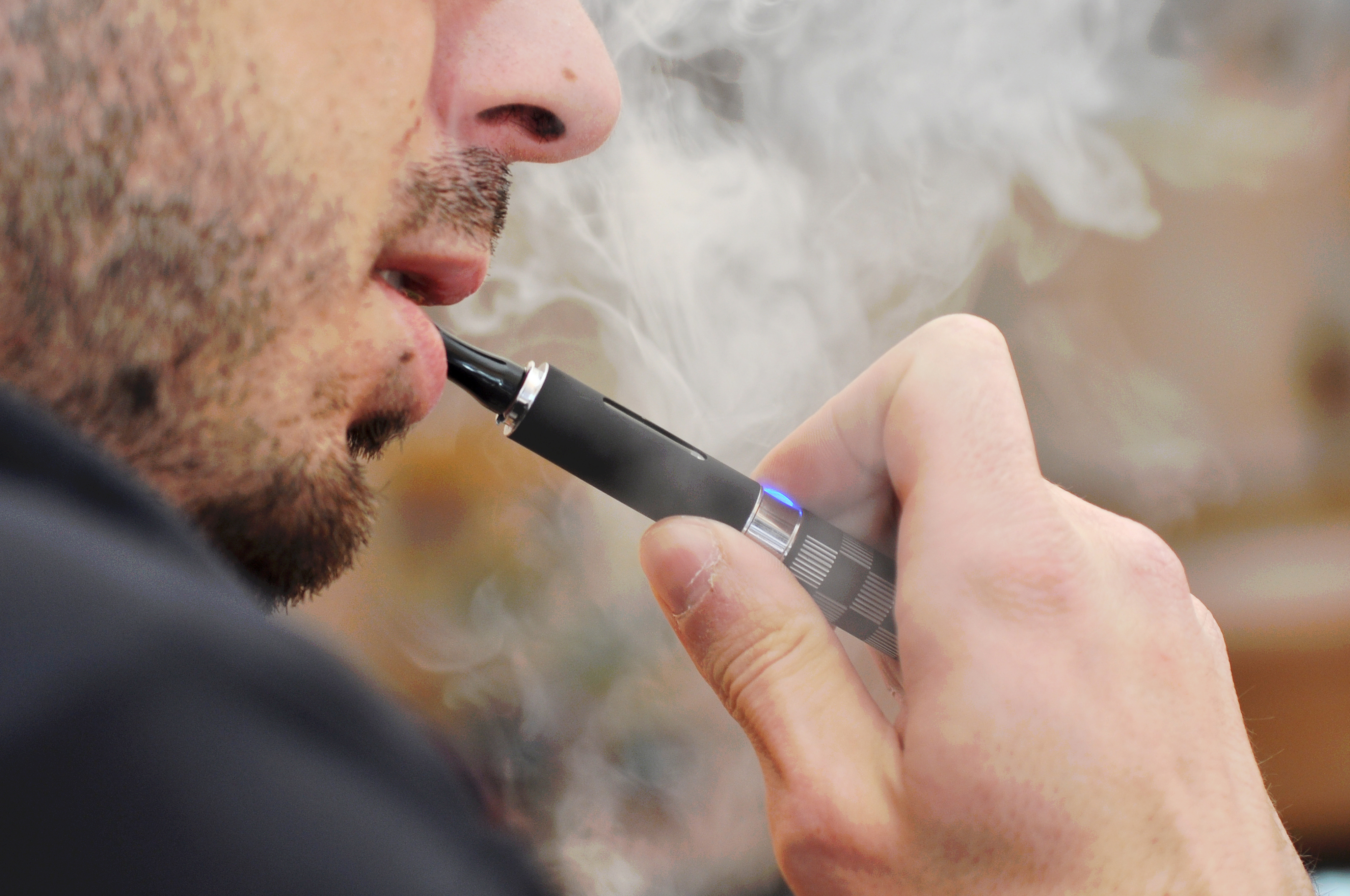 A person using an electronic cigarette, exhaling vapor
