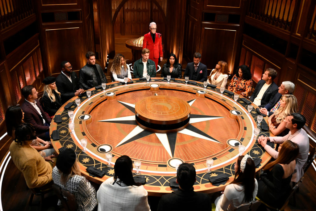 Group of individuals seated around a large circular table in a formal setting, engaging in discussion