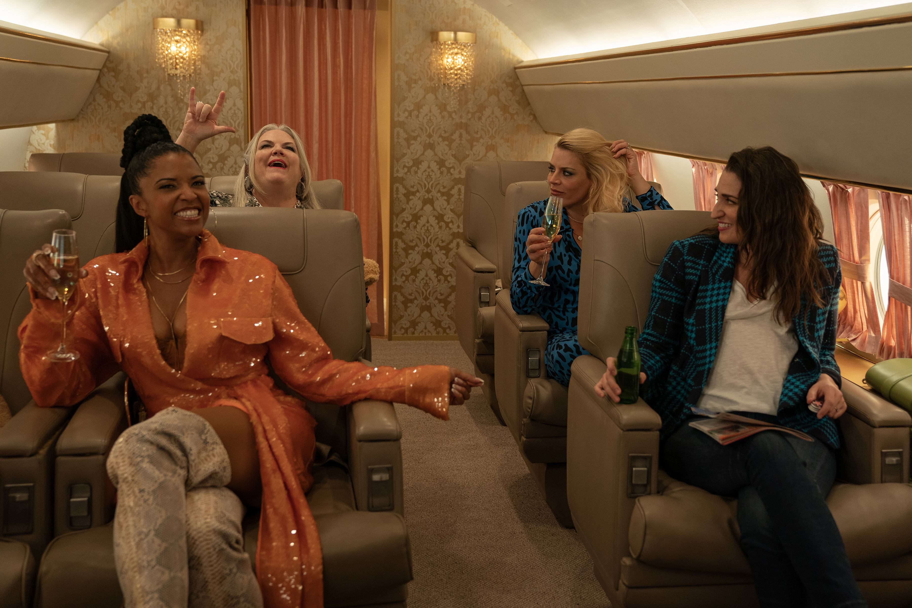 The cast of Girls5Eva sitting together on a private plane