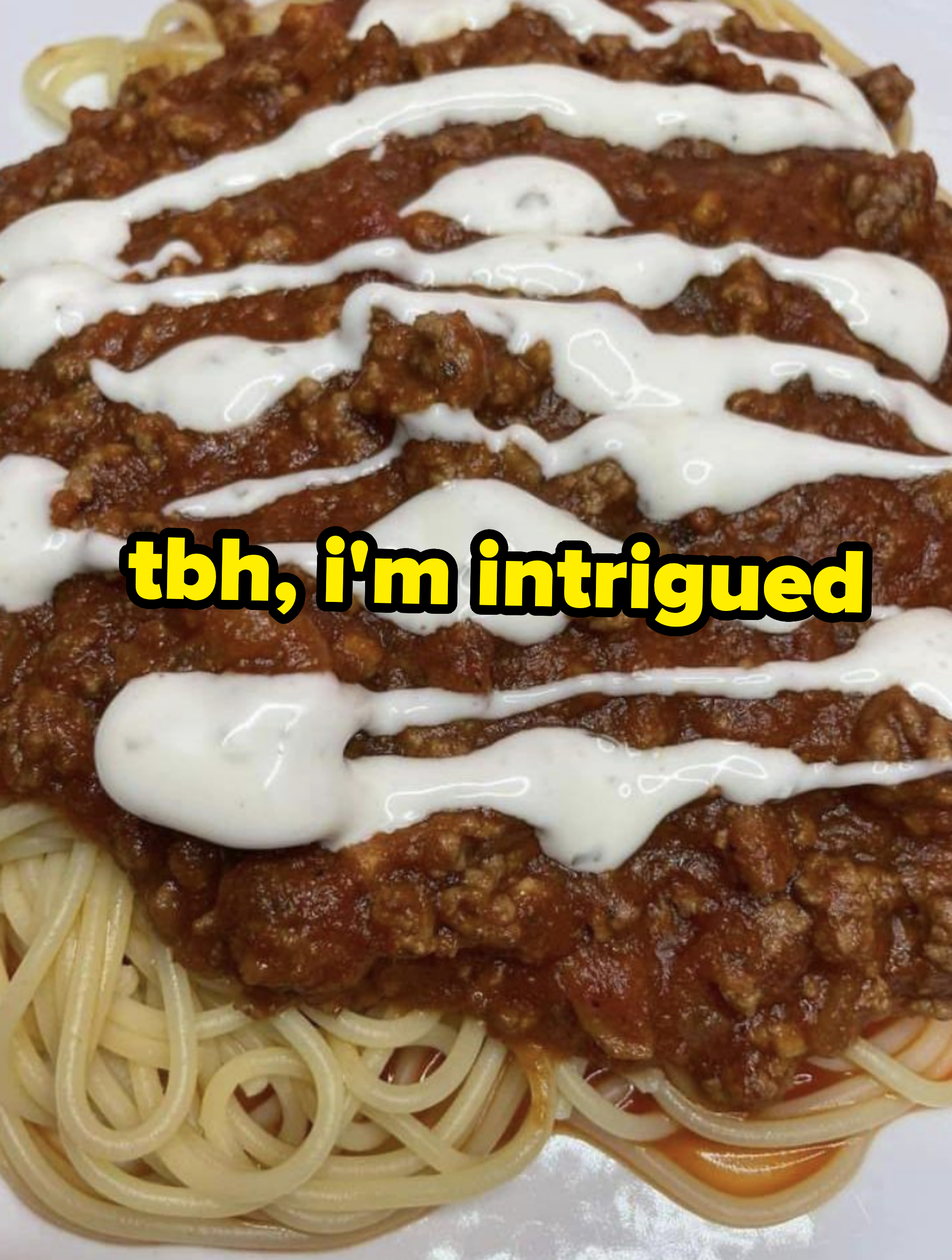 Plate of spaghetti with meat sauce and drizzled with cream on top