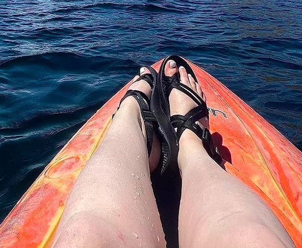 Reviewer on a kayak wearing the black sandals