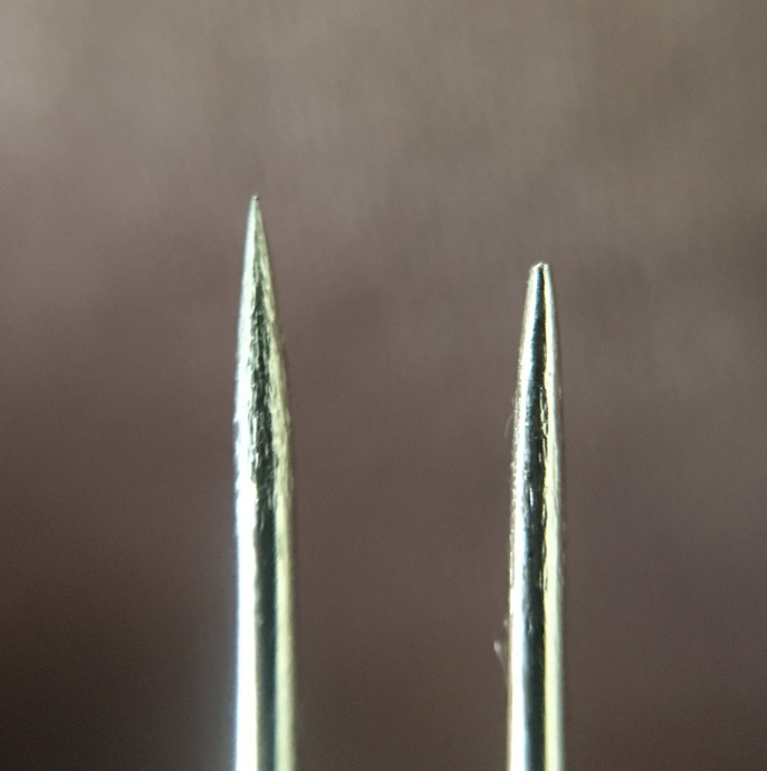 Two sewing needles close-up with one slightly in front of the other