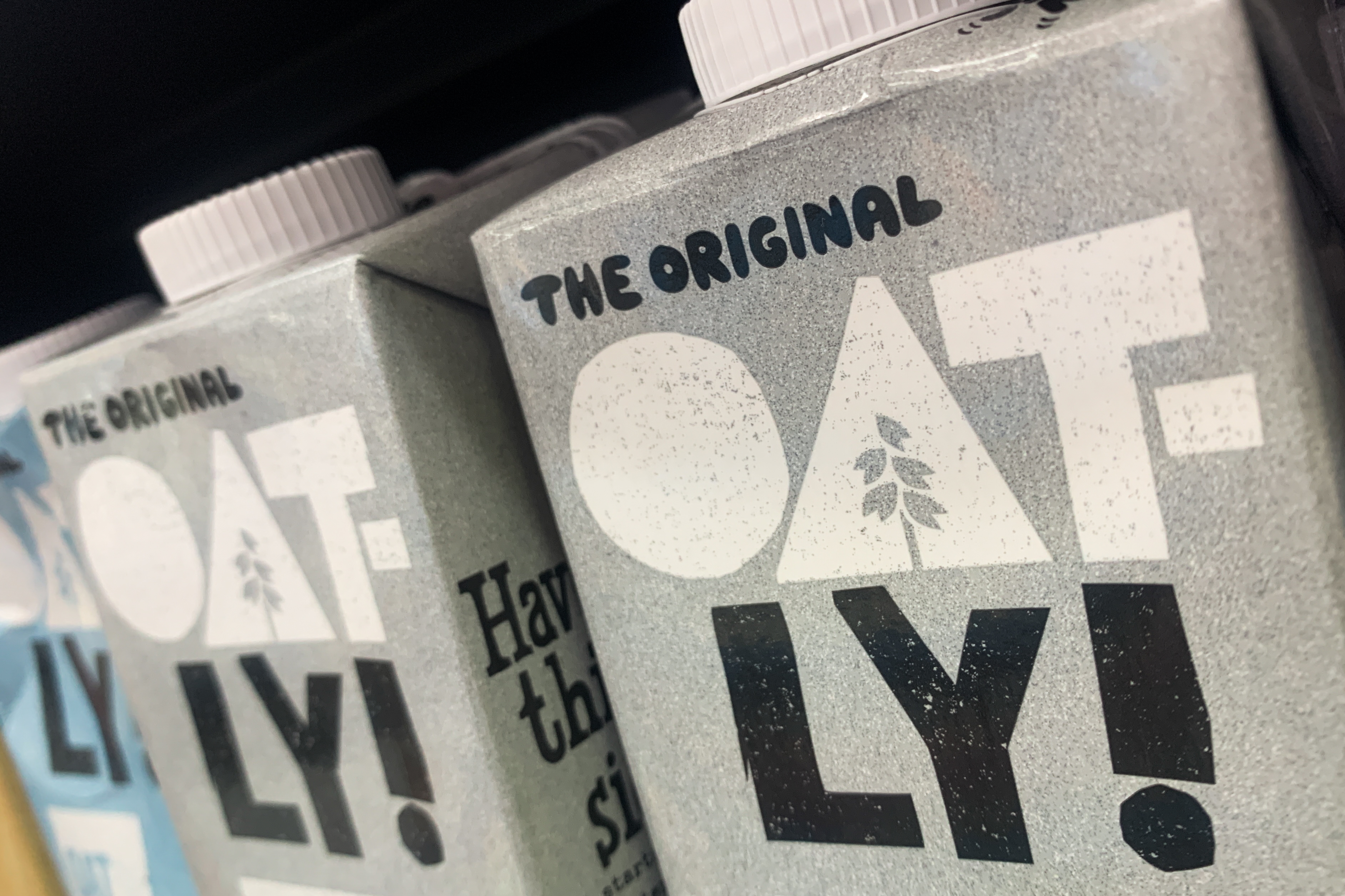 Close-up of Oatly cartons on a shelf, focusing on the brand name