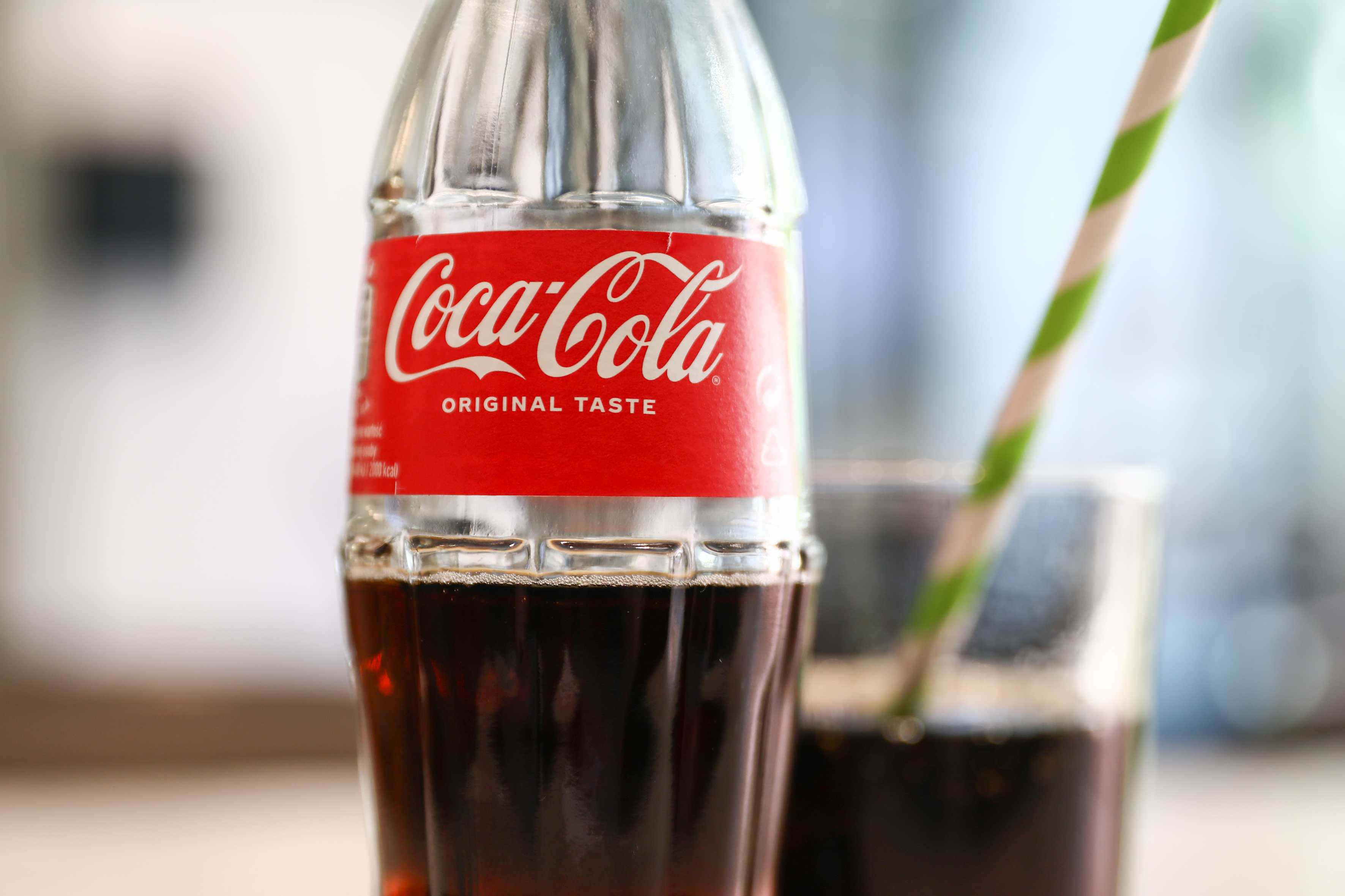 Close-up of a Coca-Cola bottle with a straw, emphasizing the brand for a work and money-related article