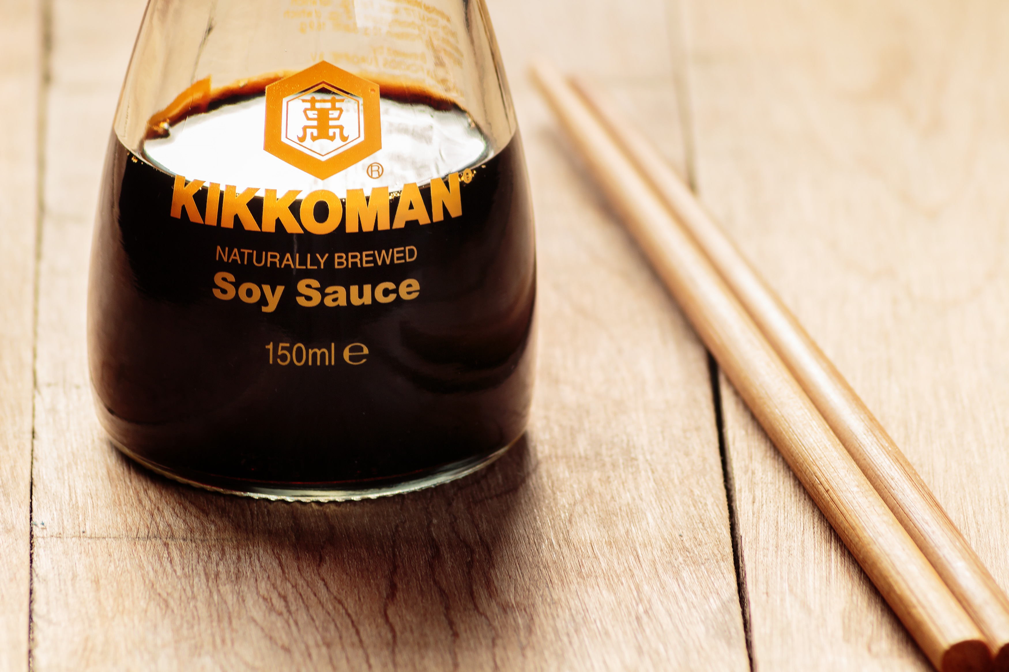 Kikkoman soy sauce bottle with chopsticks on wooden surface, related to culinary businesses