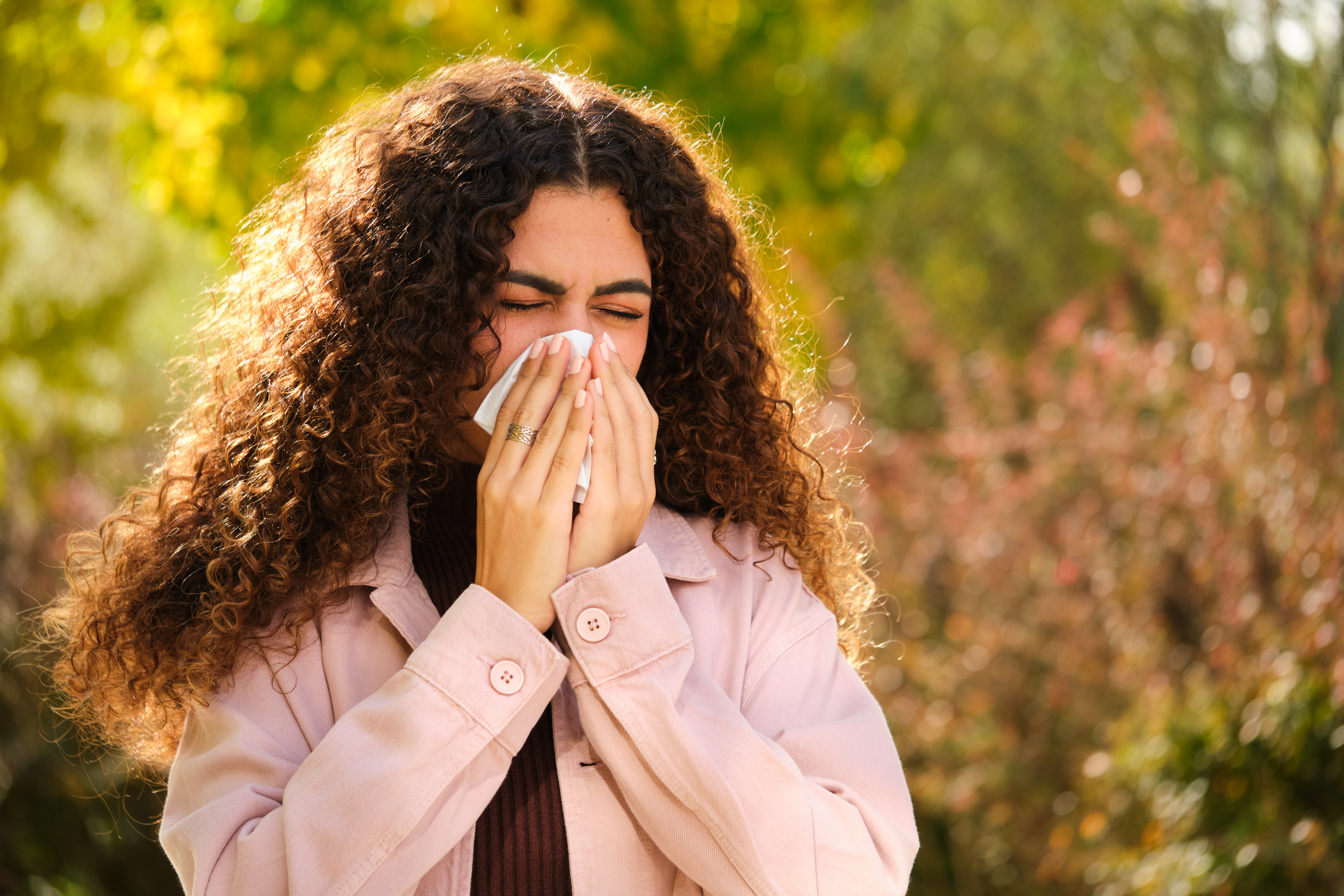 Person sneezing into a tissue, possibly due to allergies, concept for health impact on work productivity
