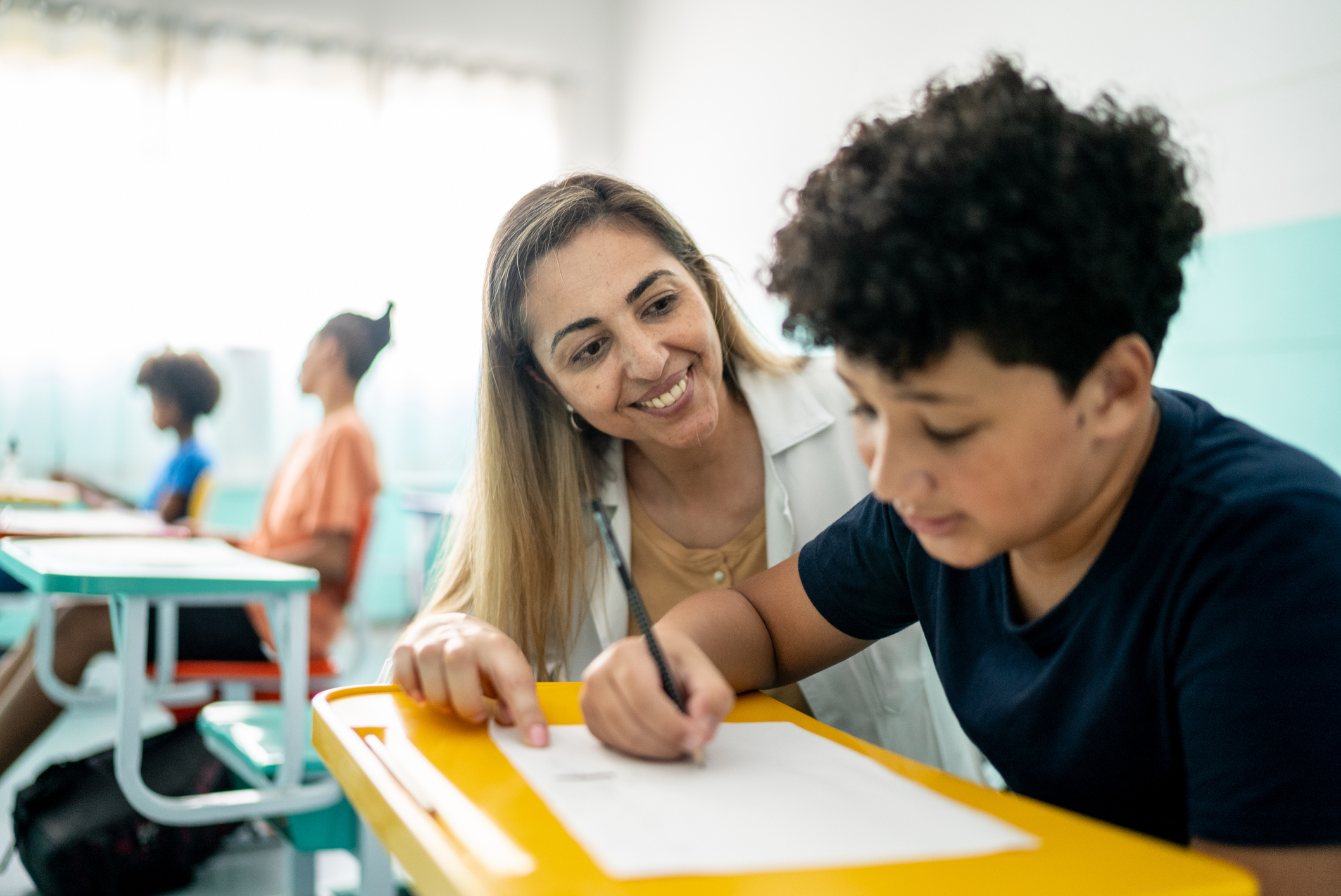 Teacher assisting a student with schoolwork in a classroom