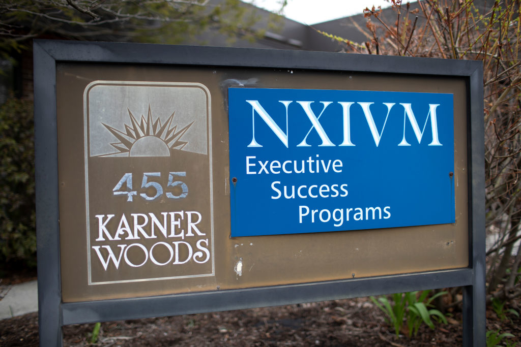 Sign for NXIVM Executive Success Programs outside Karner Woods with a logo on the left