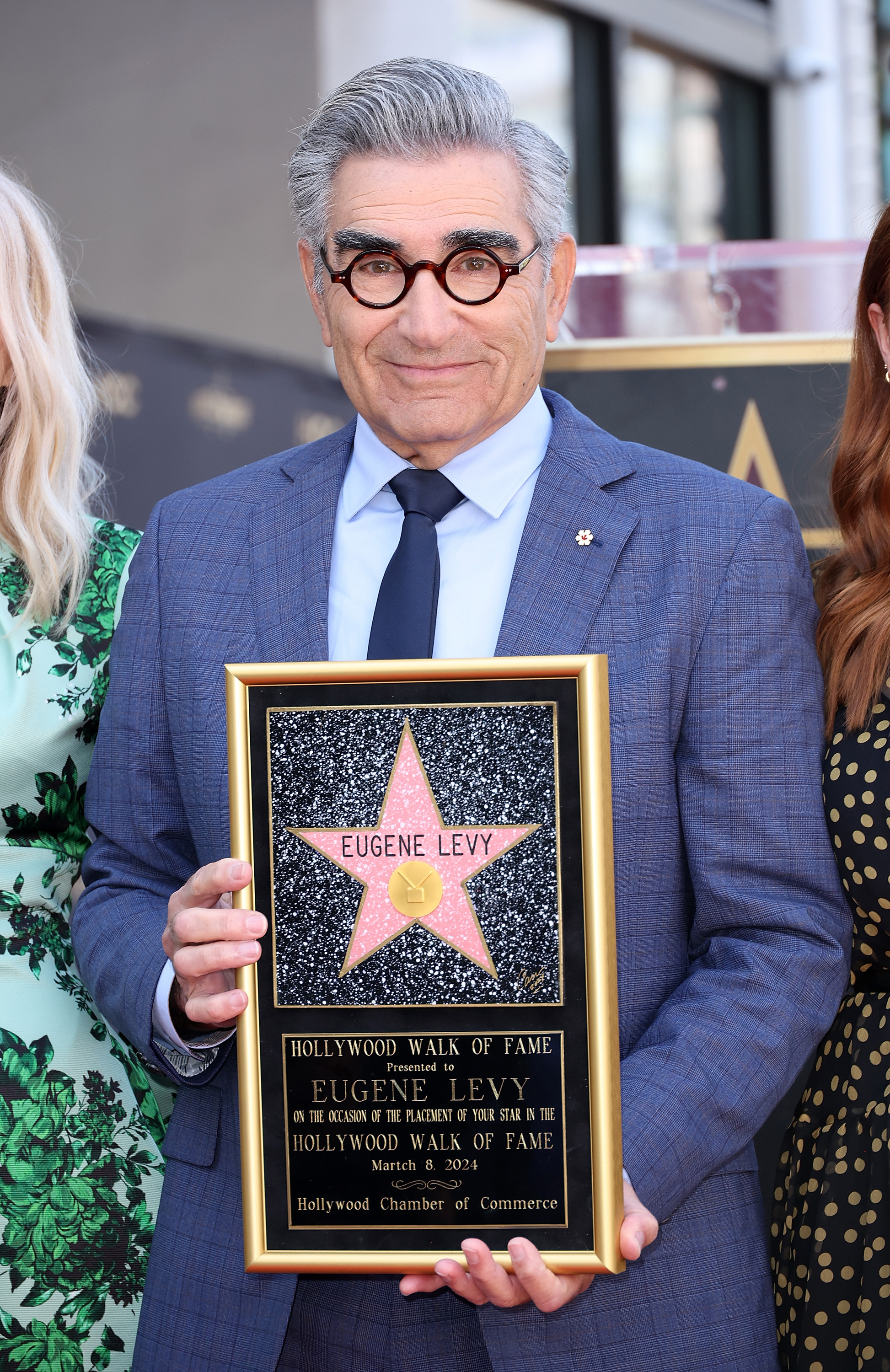 Eugene Levy in a suit holding his Hollywood Walk of Fame star plaque