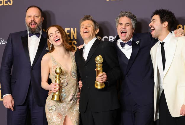 Five actors at the Golden Globes, laughing and holding awards, in formal wear