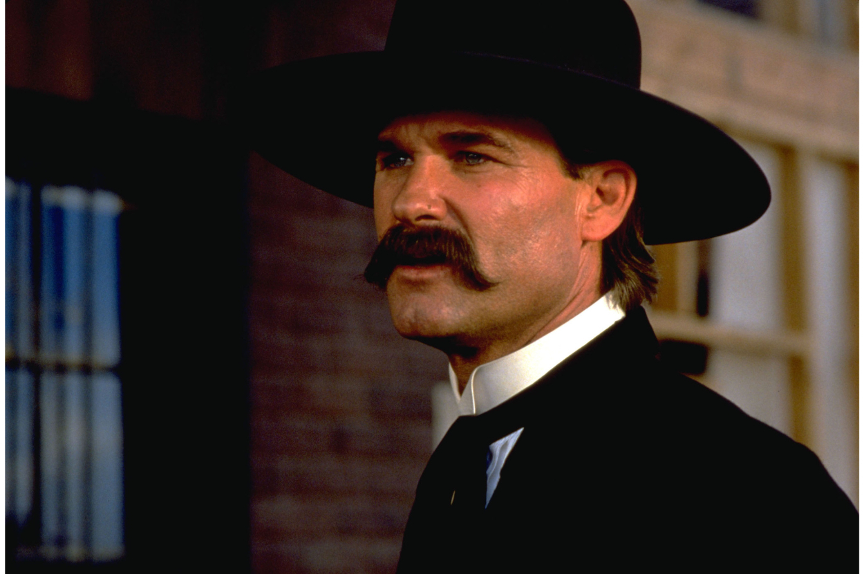 Man in period costume with a large hat and mustache, portraying a character in a film