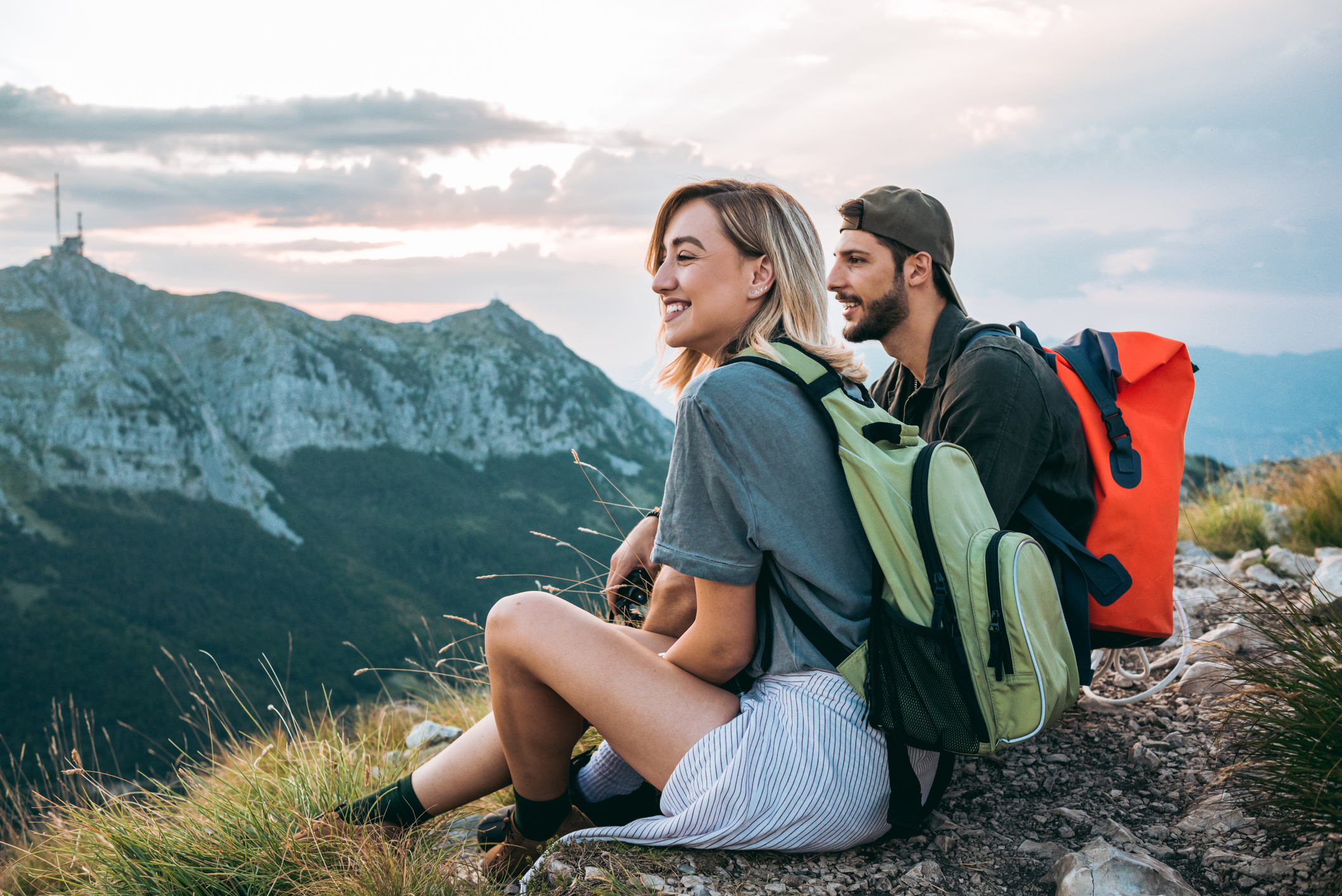 Two hikers with backpacks resting and enjoying a mountain view