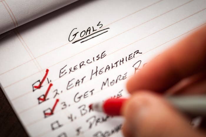 Hand writing a list of goals with checkboxes, including exercise, eating healthier, and getting more sleep