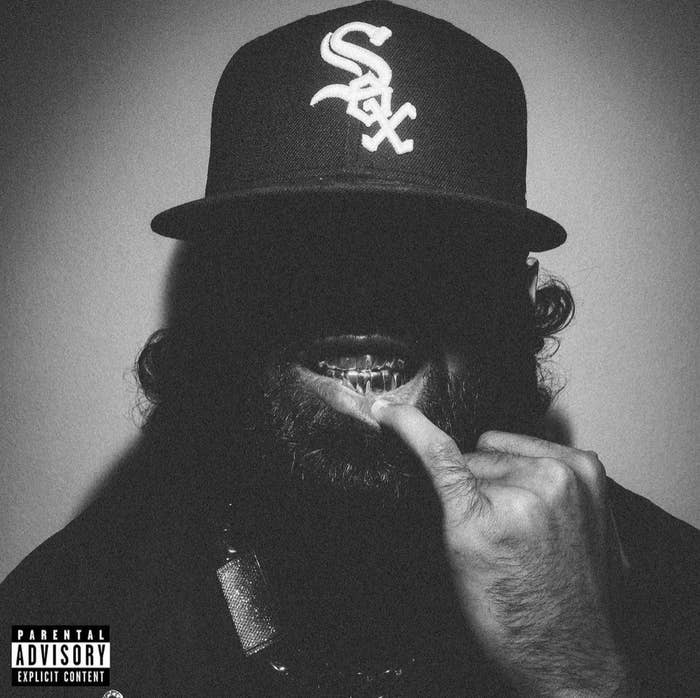 Bearded person wearing a cap flashing a sign with their fingers, with a parental advisory label on the bottom left