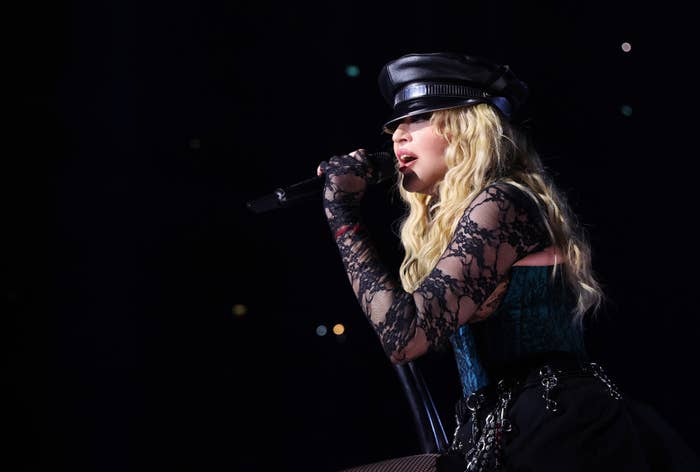 Madonna performing onstage wearing a lace top, cap, and gloves
