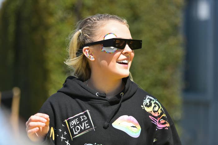closeup of jojo walking outside with sunglasses and a hoodie