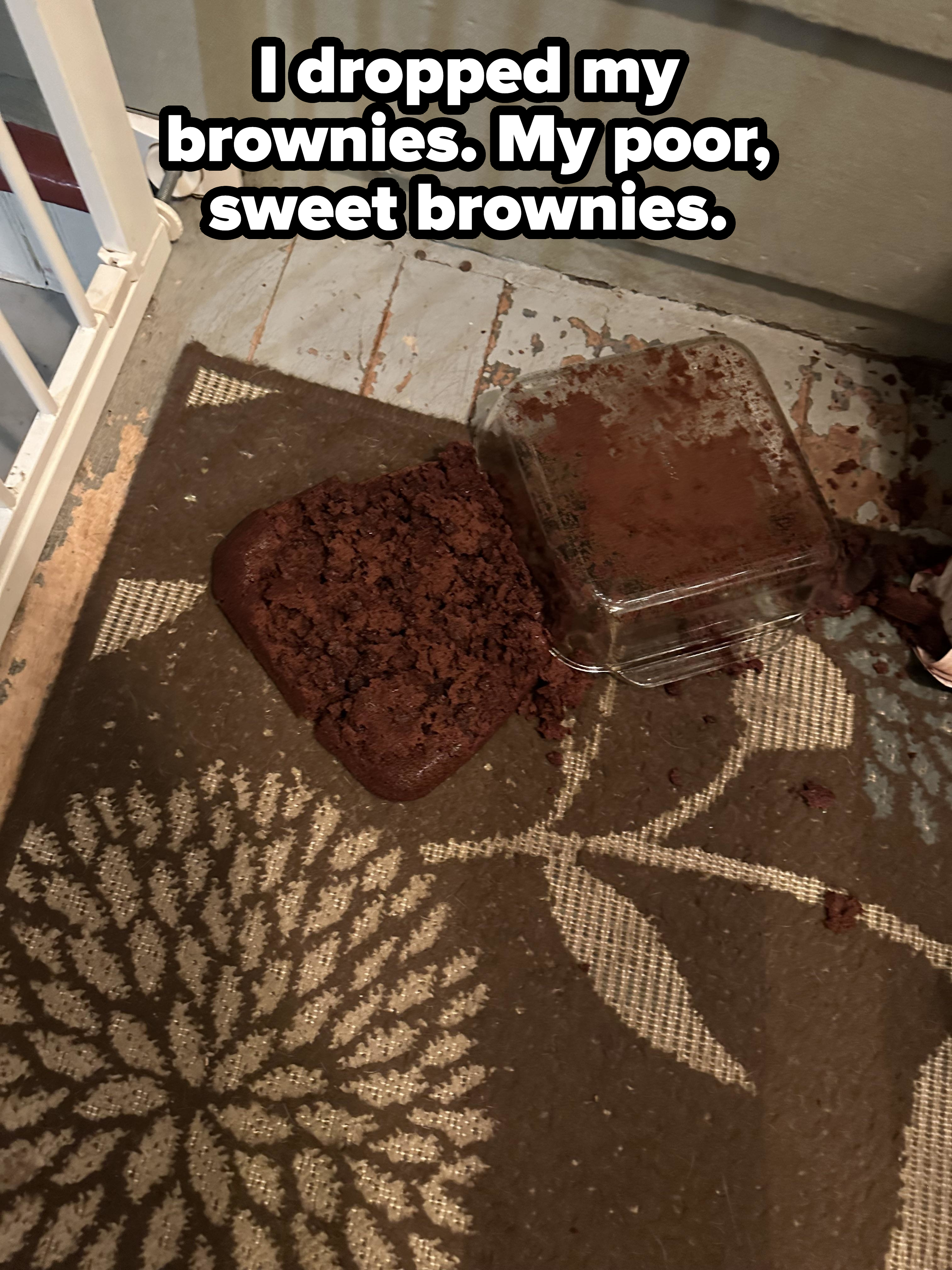 Overturned pan with spilled brownies on a patterned doormat, near a house door