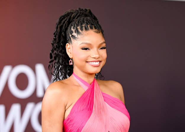 Halle Bailey smiling in a pink halterneck dress at an event
