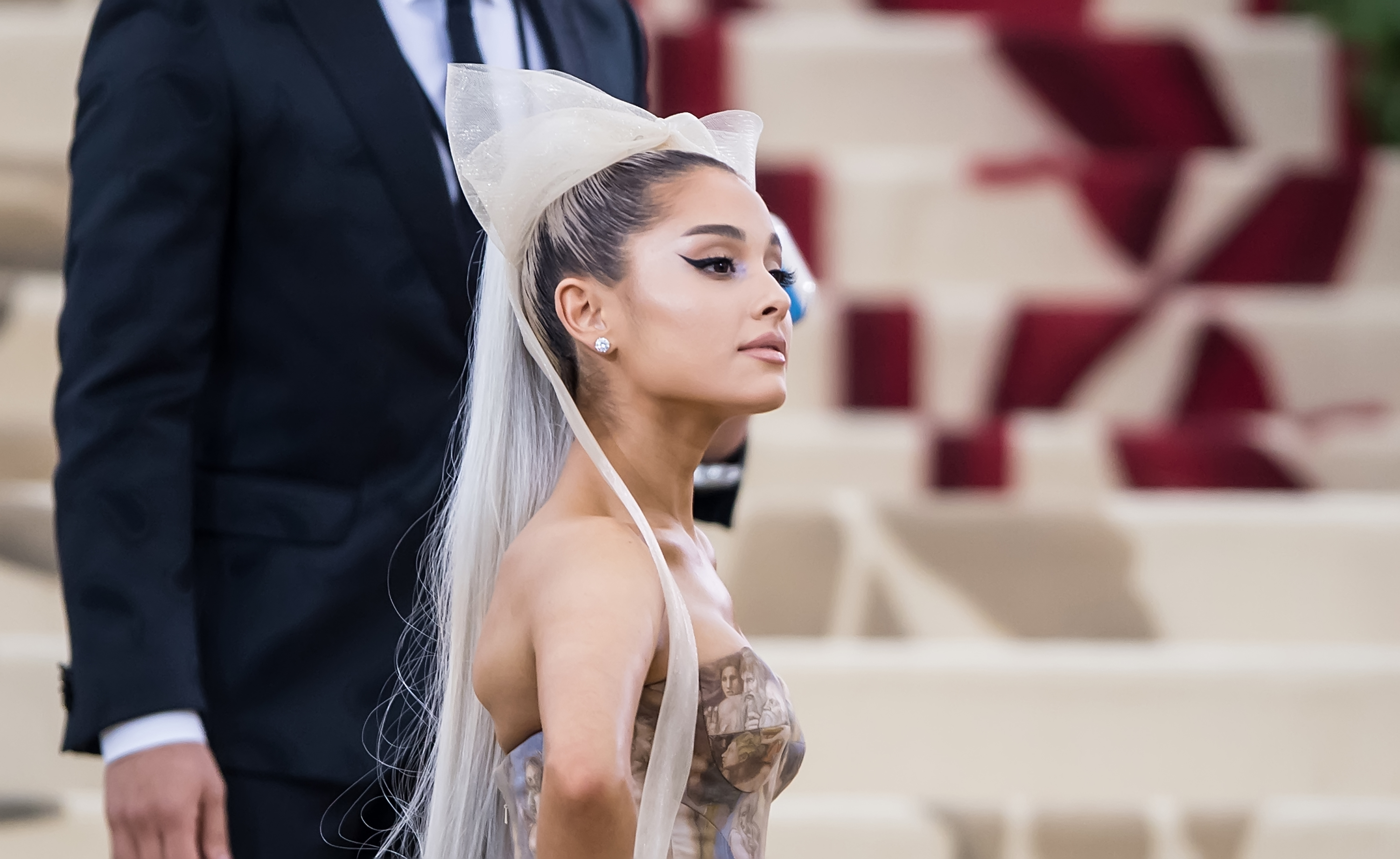 Ariana Grande at an event wearing a bow headpiece and a gown with a fitted bodice and billowing skirt