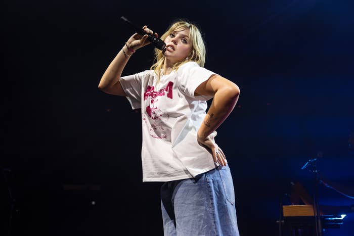 Renee in a graphic tee and jeans on stage with a microphone