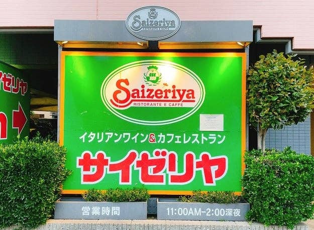 Saizeriya restaurant signboard with logo, Japanese text, and business hours displayed on the storefront