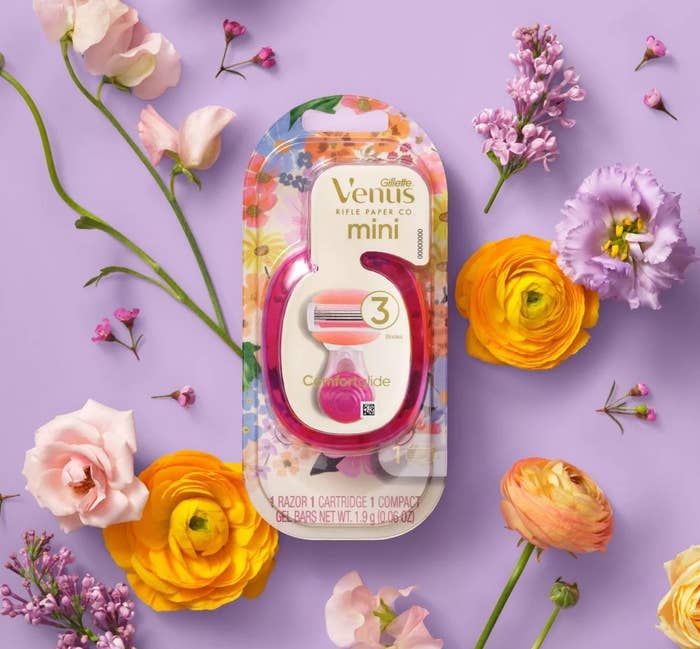 Floral-themed Venus mini razor surrounded by assorted flowers on a purple background