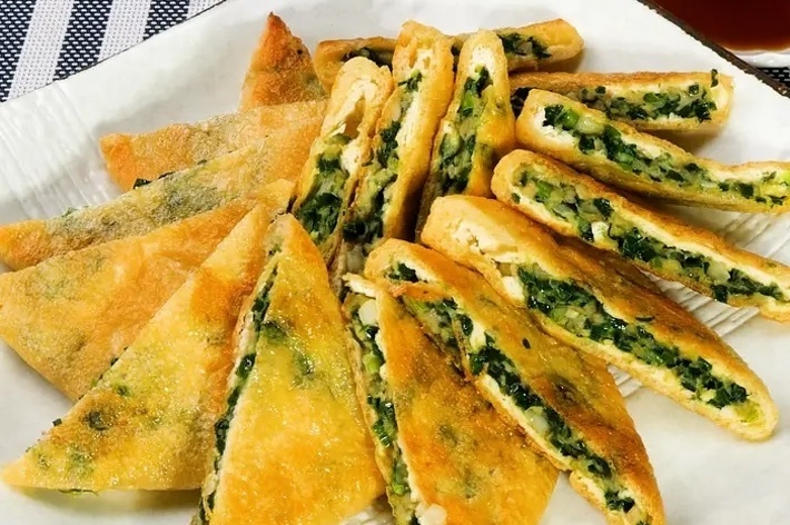 ひだのある三角形のパイがたくさん並べられており、中にはチーズと野菜が詰まっている。