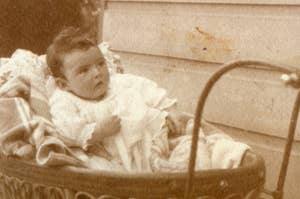 Infant in vintage clothing lying in an antique bassinet