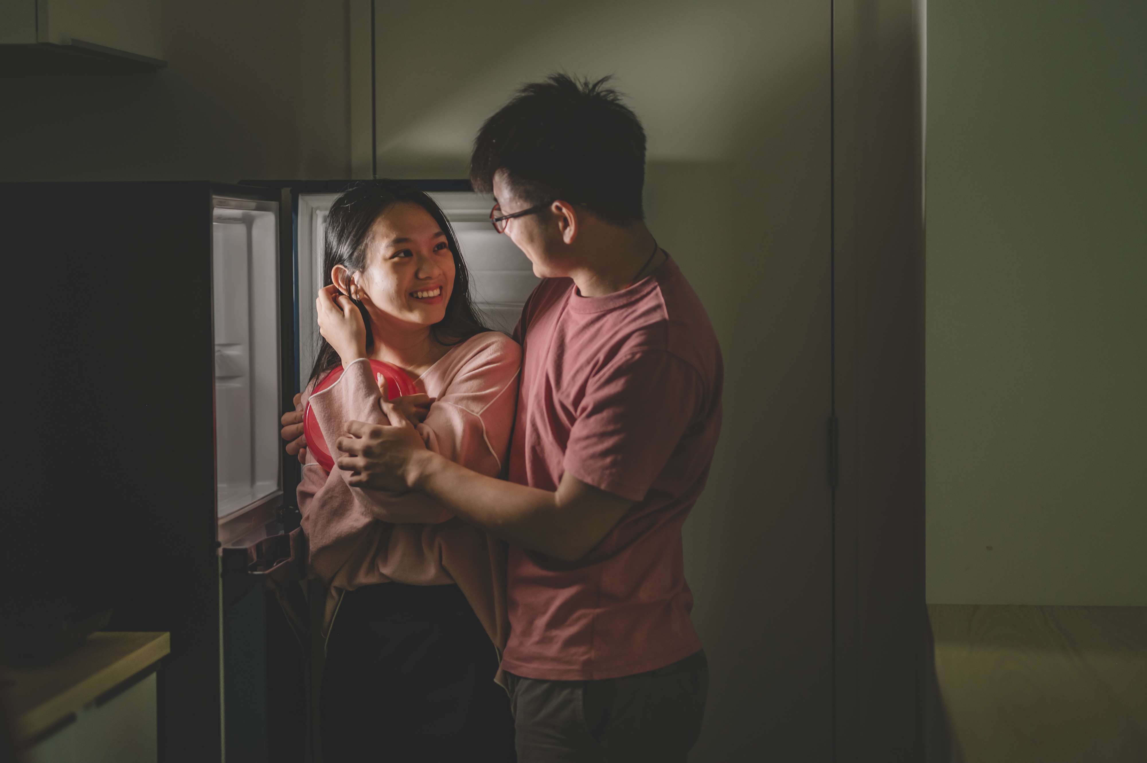 A couple engaging in a playful, romantic moment in a kitchen