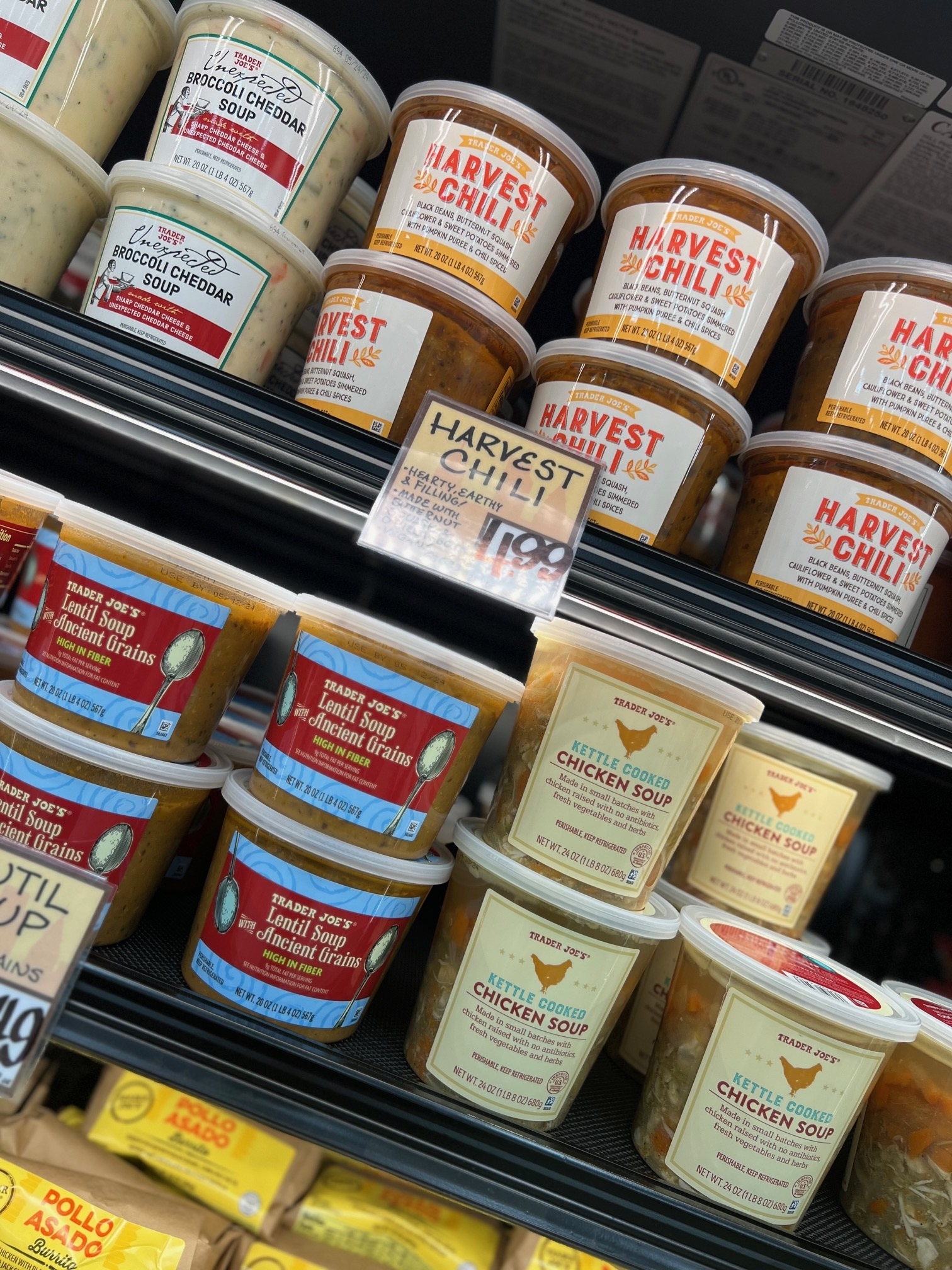 Assorted pre-packaged soups on grocery shelves, including chicken soup and harvest chili