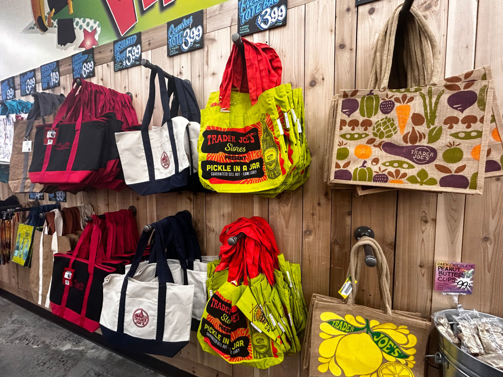 Wall display of various reusable shopping bags with assorted designs and slogans