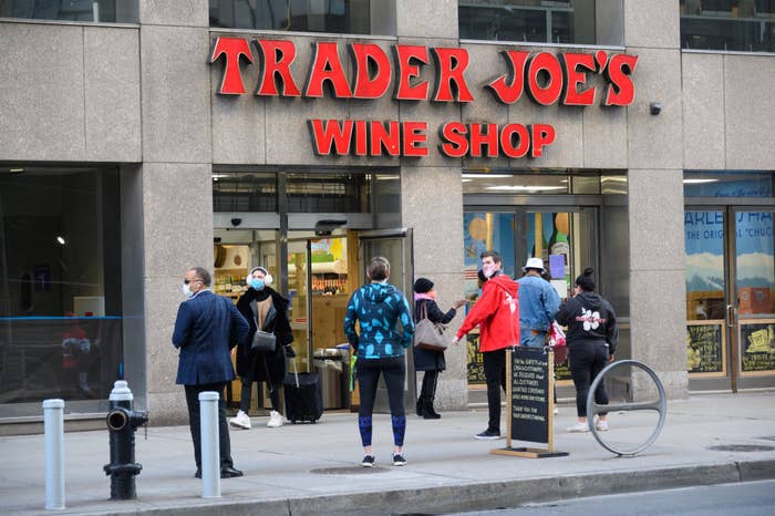 People outside Trader Joe&#x27;s Wine Shop with a sandwich board sign