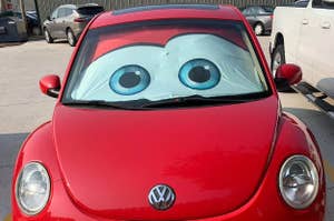 Red Volkswagen Beetle with large cartoon eyes on windshield for sun protection