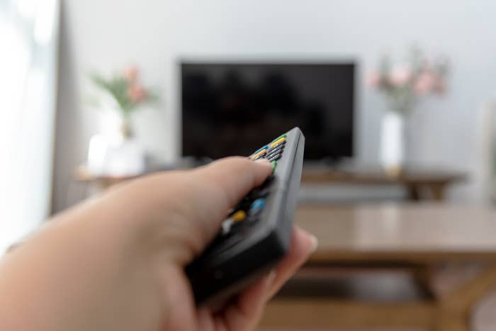 Person pointing a remote at a television screen in a living room setting