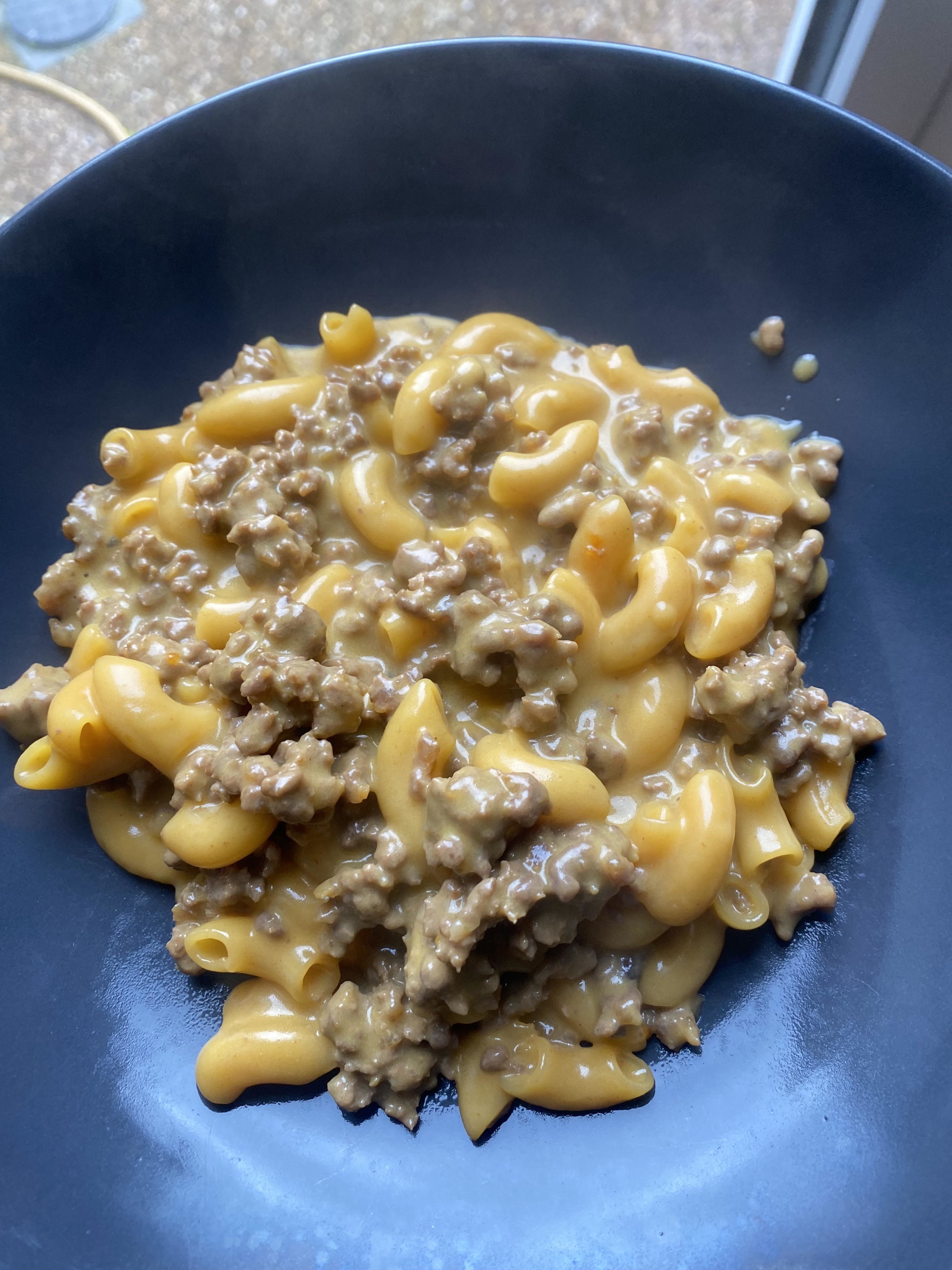 A bowl of macaroni with creamy cheese sauce and ground beef topping