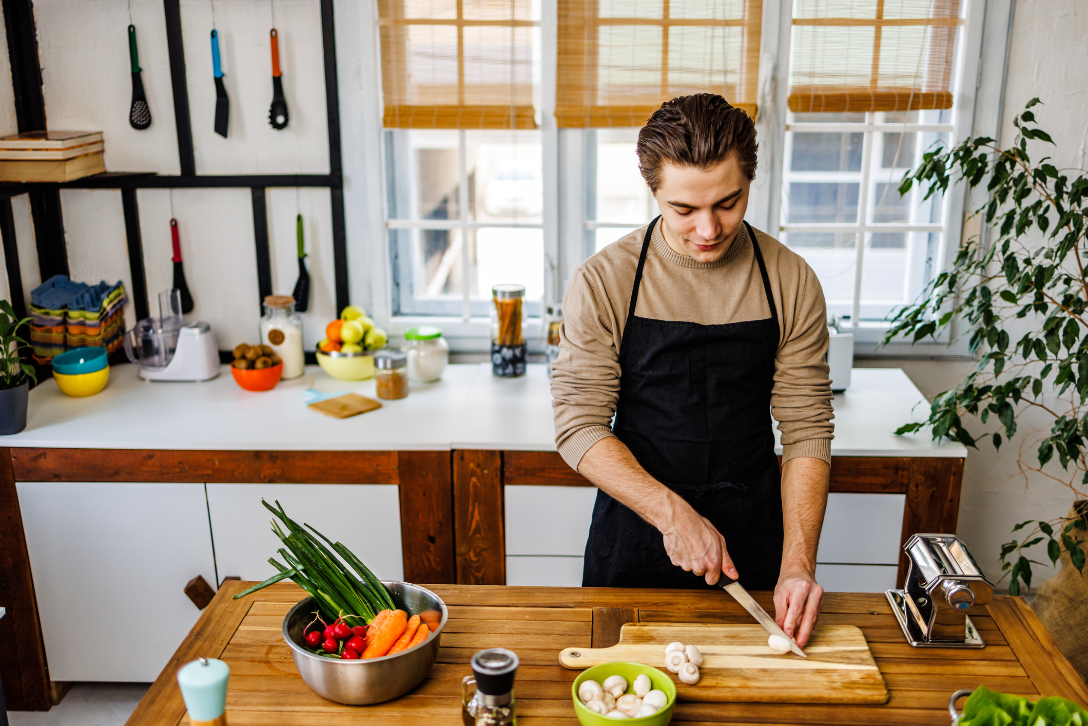 Man in apron chops vegetables on kitchen counter for meal prep