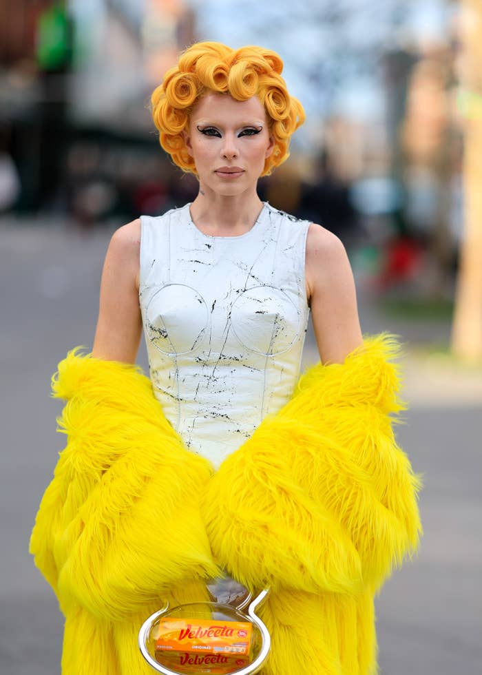 Woman in avant-garde outfit with sculpted hair and feathered skirt