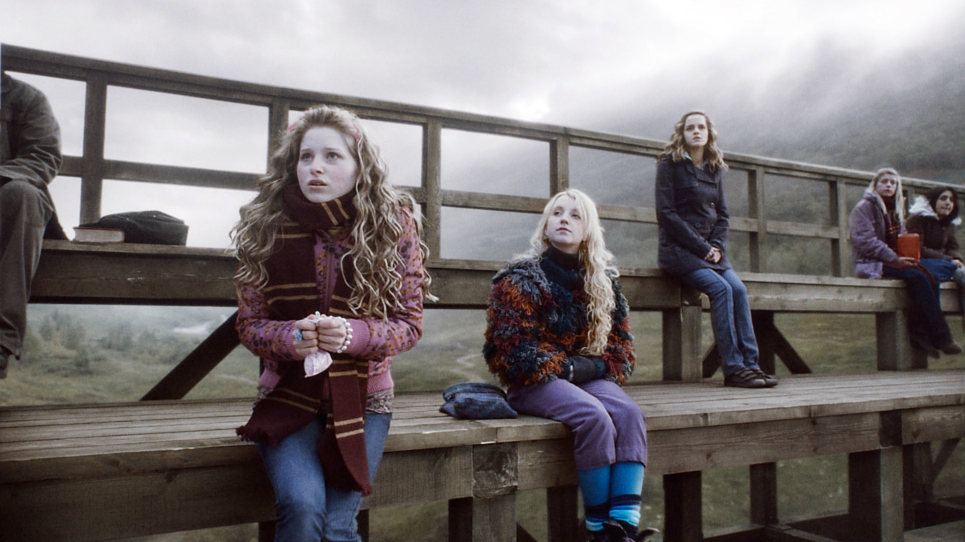 Emma Watson and Evanna Lynch and Jesse in a scene from Harry Potter, sitting on a bench looking concerned