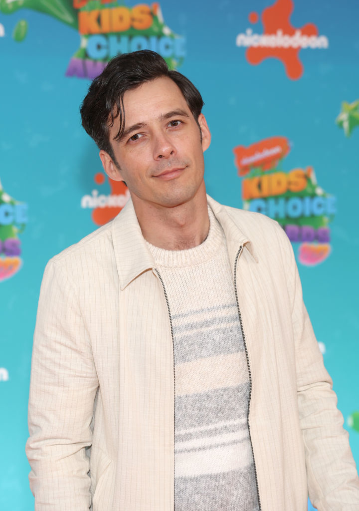 Matthew posing on the Kids&#x27; Choice Awards backdrop, wearing a jacket over a striped sweater