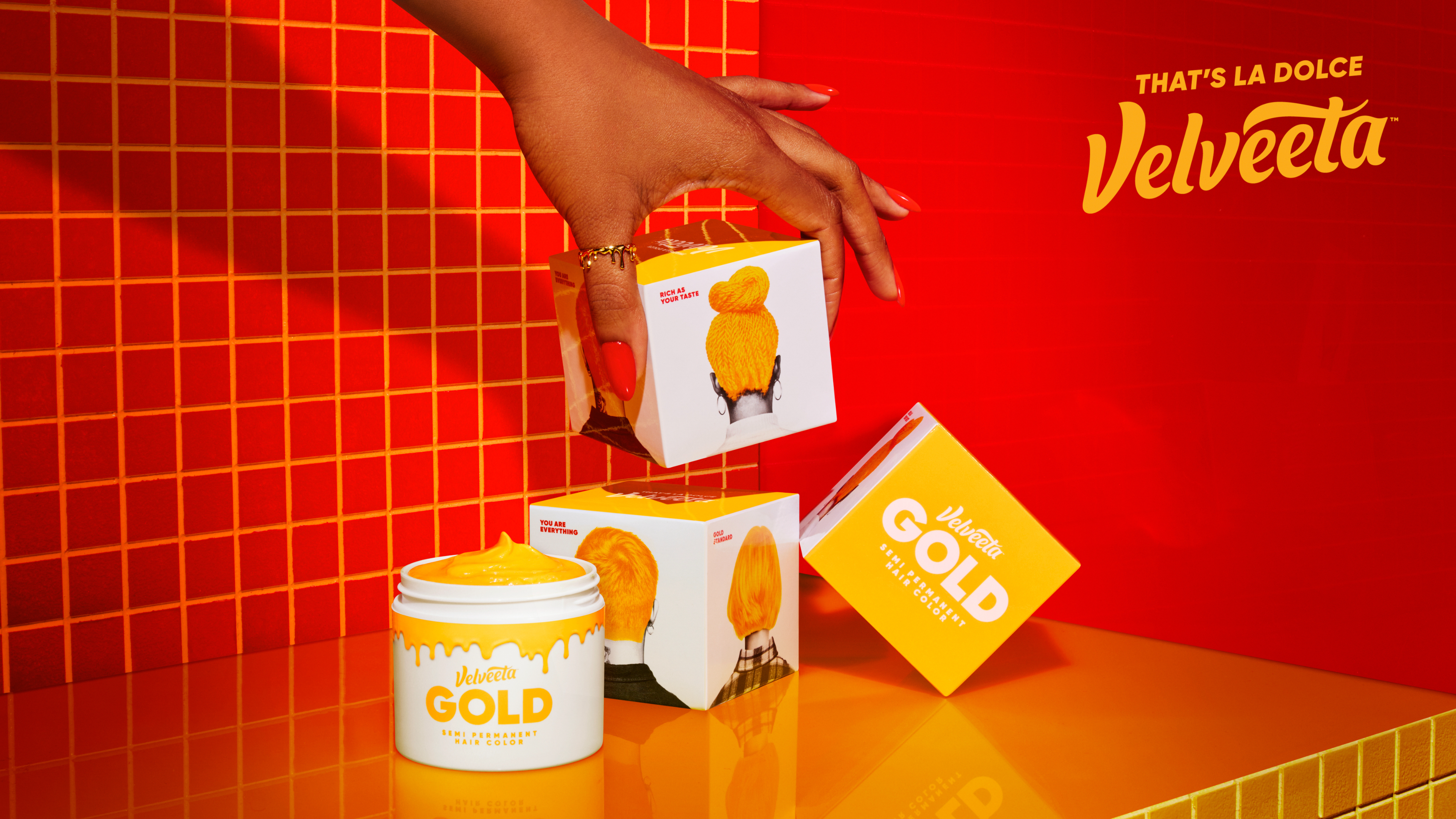 Hand reaching for a Velveeta box in front of a promotional backdrop with products displayed