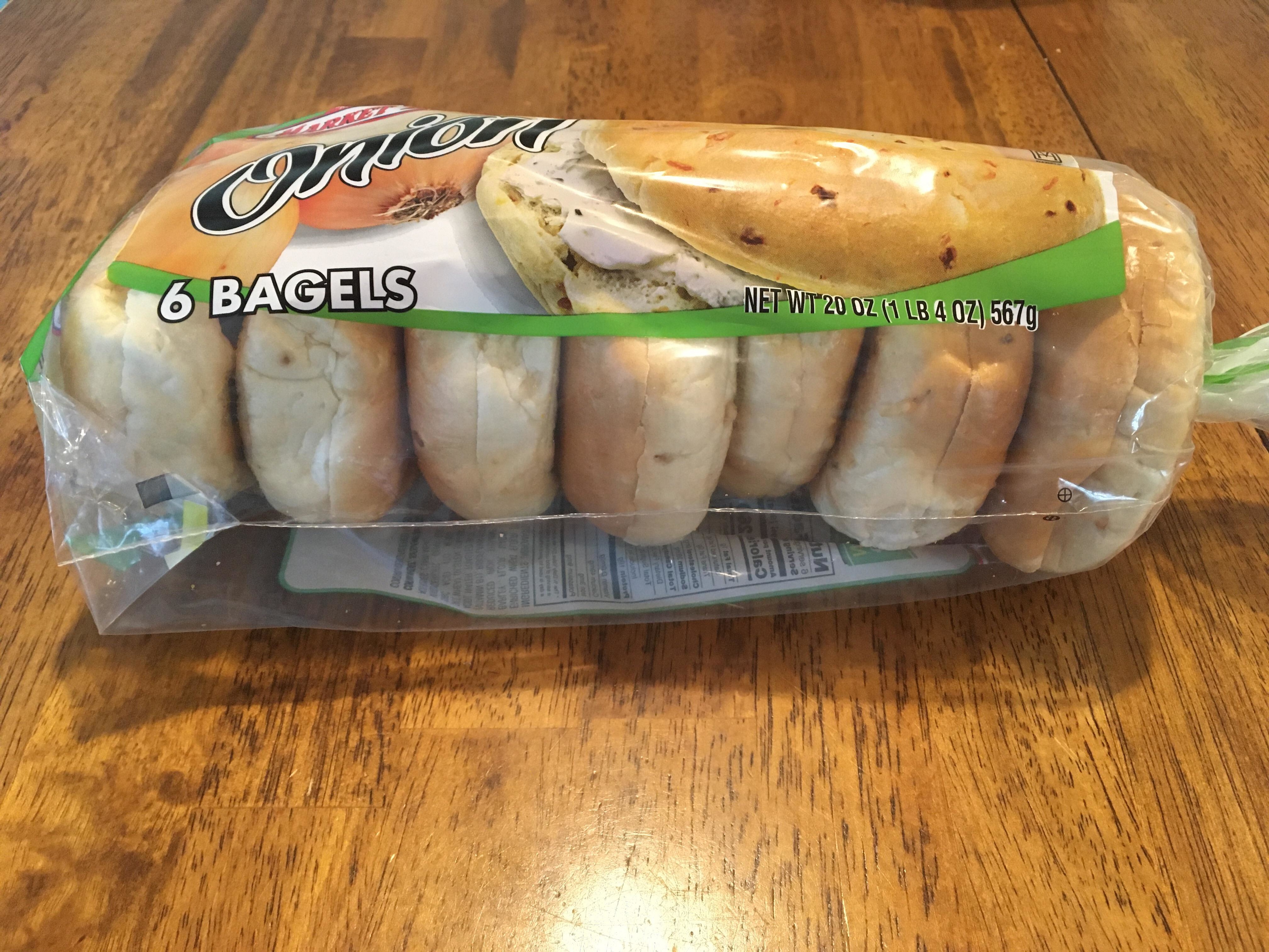 A sealed package of onion bagels on a wooden table
