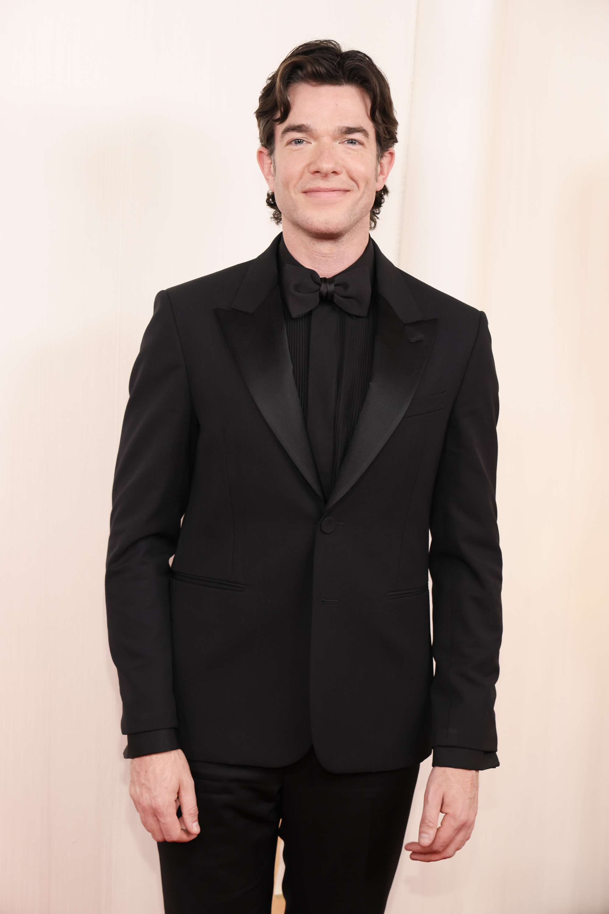 Man in a classic black tuxedo with bow tie standing on a red carpet